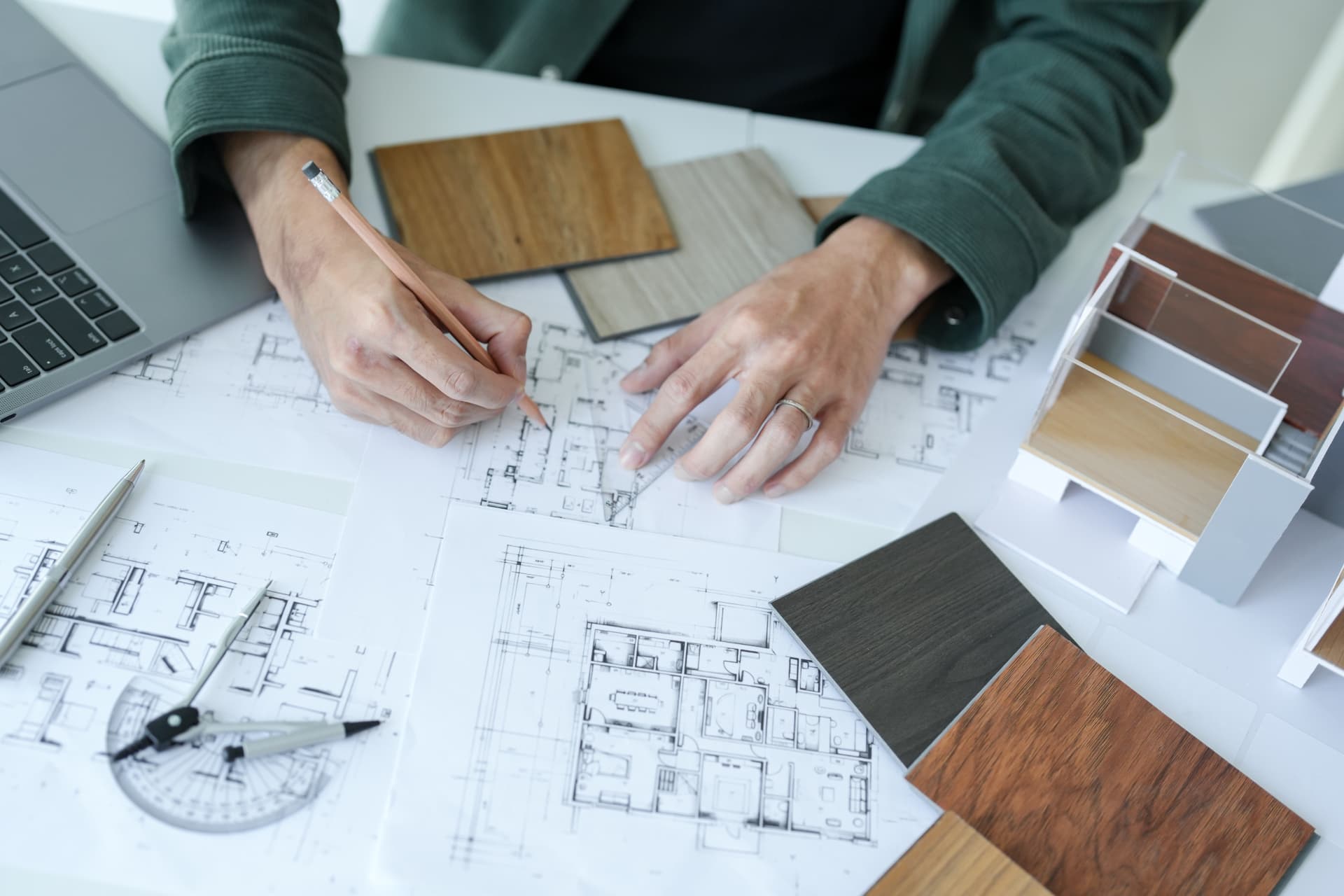 Interior project management: designer working over floor plans, material samples and a scale model